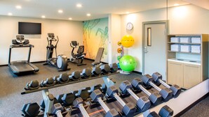 Et fitnessrum med løbebånd, crosstrainere og mange forskellige håndvægte.