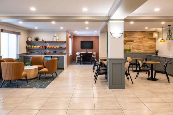 A hotel lobby with a seating area, a bar, and a television.