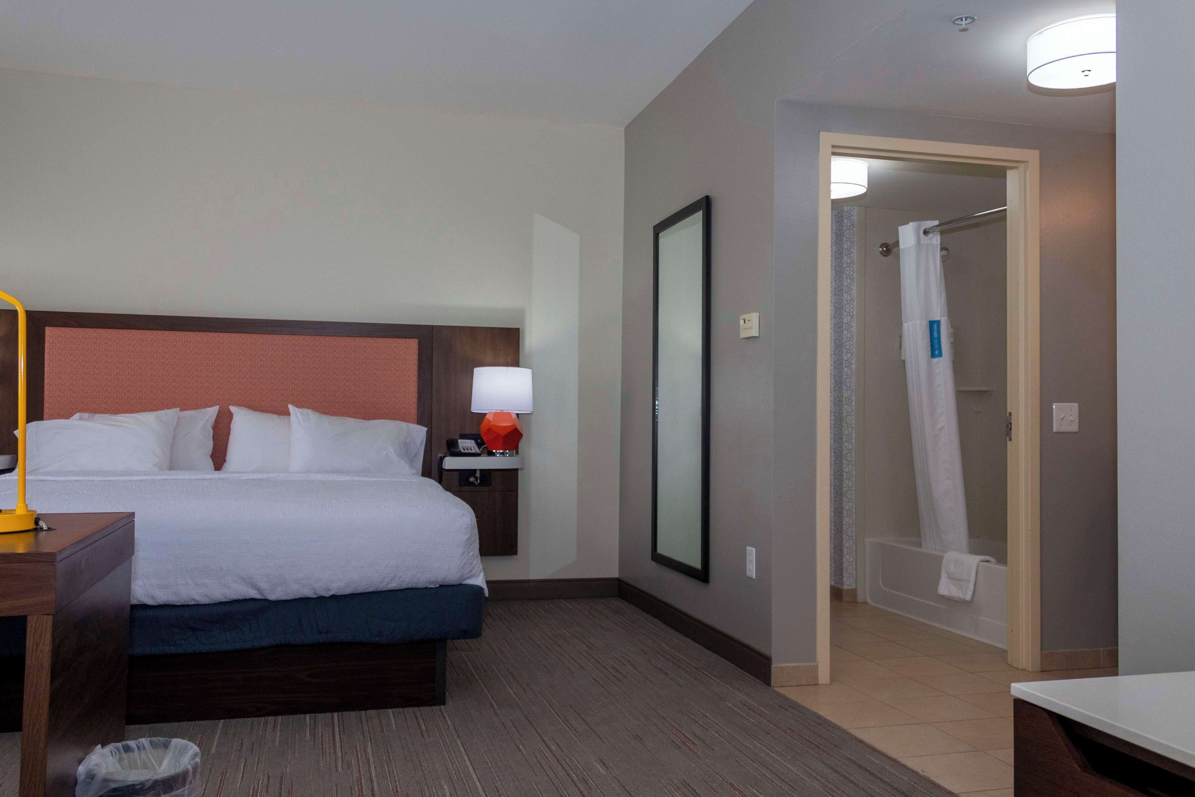 Une chambre d’hôtel comprenant un lit, une table de chevet, une lampe et un espace douche.