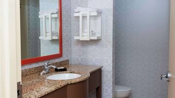 A bathroom with a granite countertop sink, a mirror with a red frame, and two towel racks on the wall.