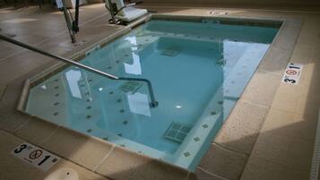 Una piscina pequeña en el interior con un indicador de profundidad de 0,9 metros, una escalera de piscina y un cartel de prohibido bucear.