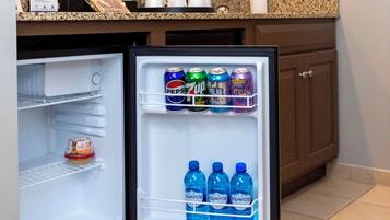 Un refrigerador pequeño con bebidas y un envase de helado.