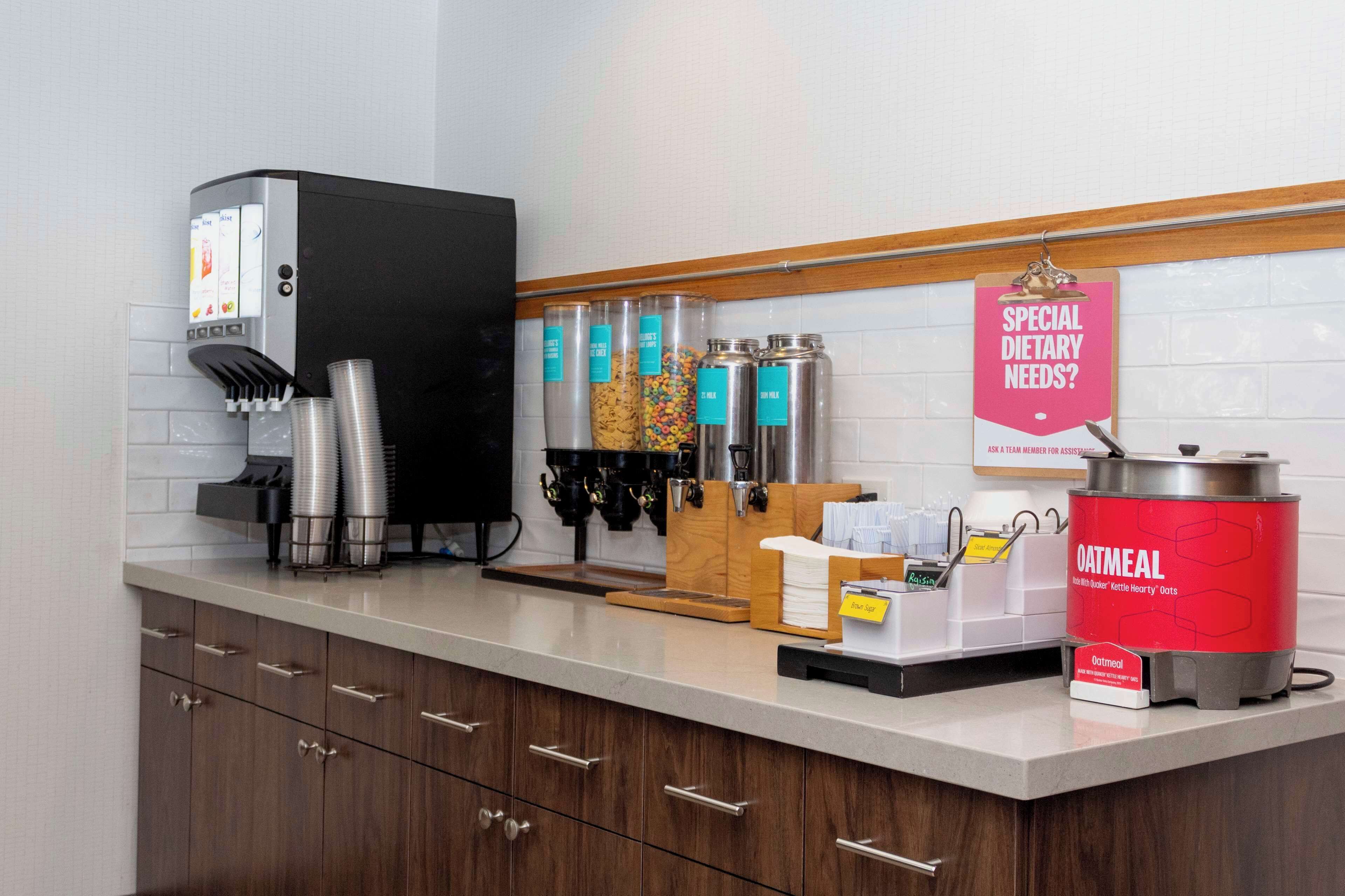 Un área de cocina con cafetera, dispensadores y un cartel para necesidades dietéticas especiales.