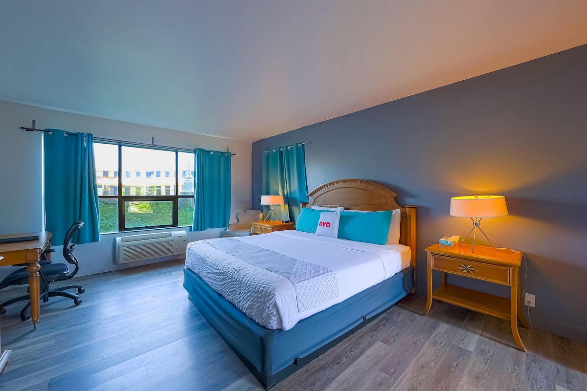 Une chambre d’hôtel avec un grand lit, un bureau, une chaise et une table de chevet avec une lampe.