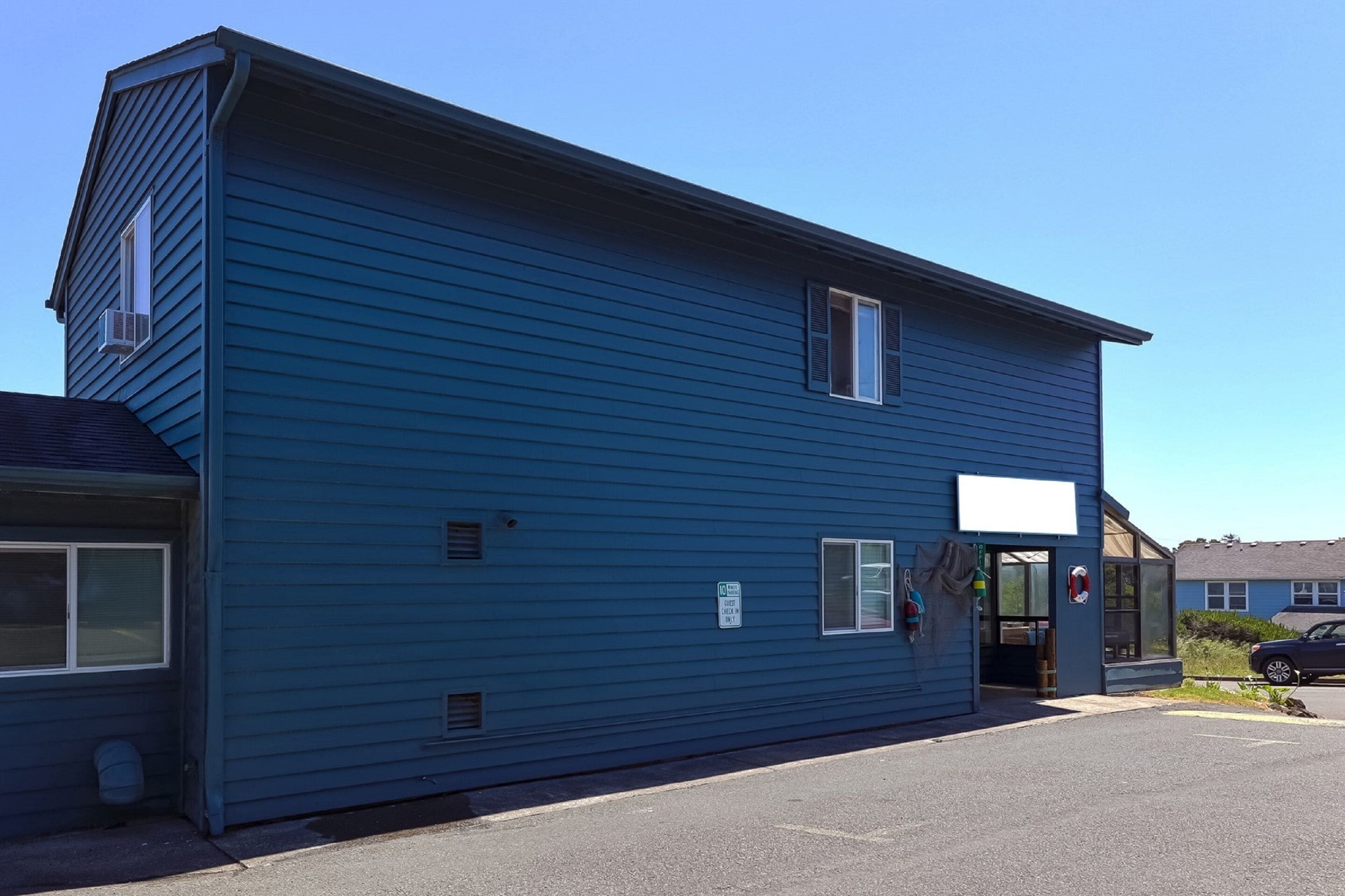 A two-story building with a blue exterior, a garage door, and a small entrance.