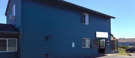 A two-story building with a blue exterior, a garage door, and a small entrance.