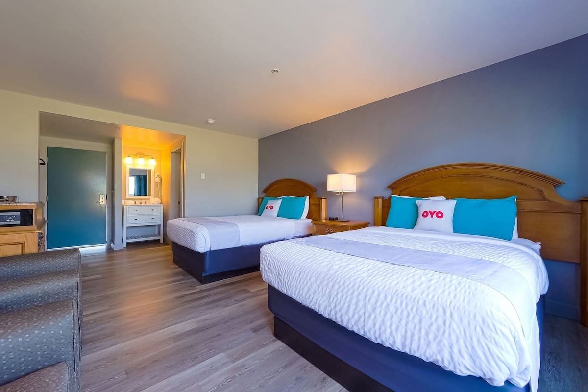 Une chambre d’hôtel avec deux lits, un bureau, une chaise et une salle de bain.