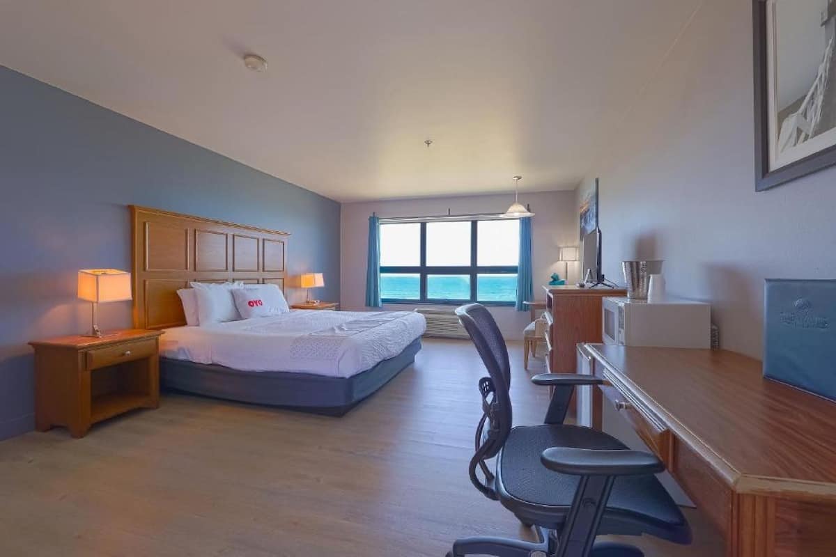 Une chambre d’hôtel avec un lit, un bureau, une chaise et une vue sur la mer.