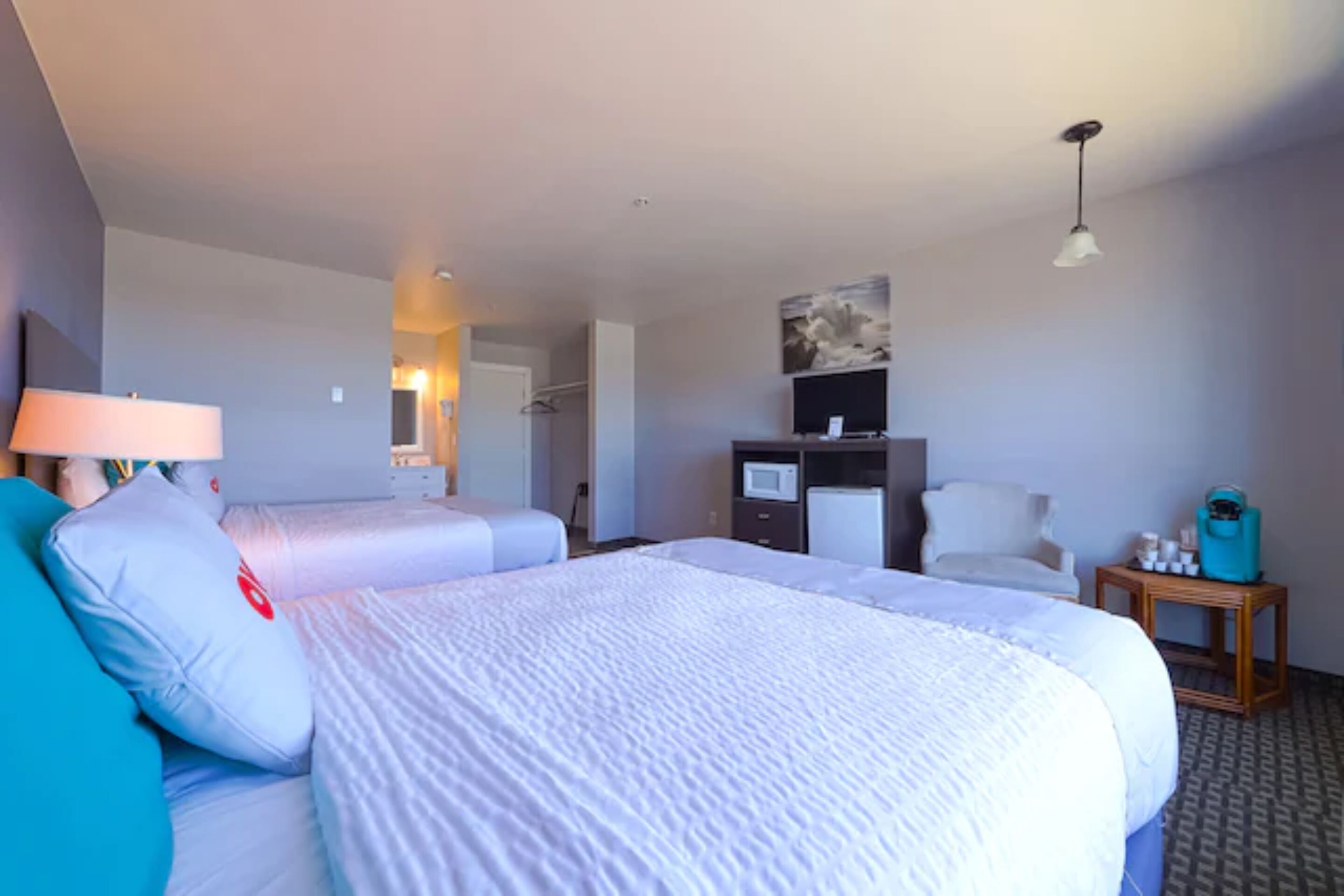 Ein Hotelzimmer mit zwei Betten, einem Schreibtisch, einem Stuhl, einem Fernseher und einer Lampe.
