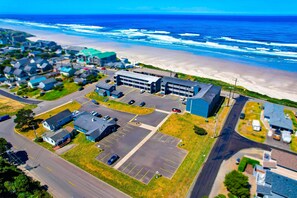 An aerial view of a coastal town with a large building complex, parking lots, and a beach. - Waves Hotel NYE Beach - Newport OR (Newport)