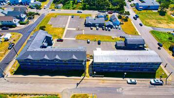 An aerial view of a parking lot with several buildings, including a large blue structure and a smaller white building.