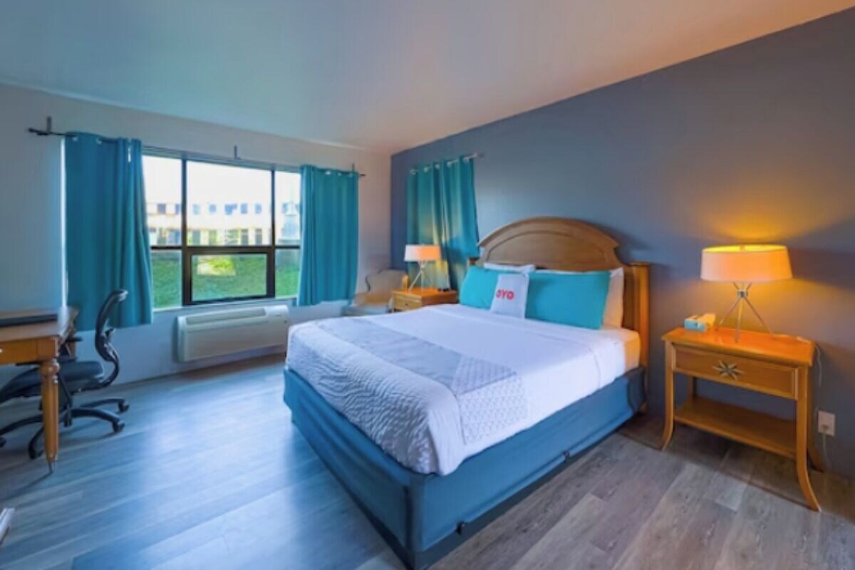 A hotel room with a large bed, two bedside tables, a desk, and a chair.