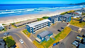 An aerial view of a coastal building complex with parking, a beach, and ocean views. - Waves Hotel NYE Beach - Newport OR (Newport)
