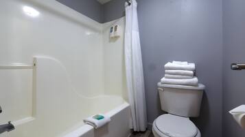 A bathroom with a bathtub, toilet, and hand soap dispensers.