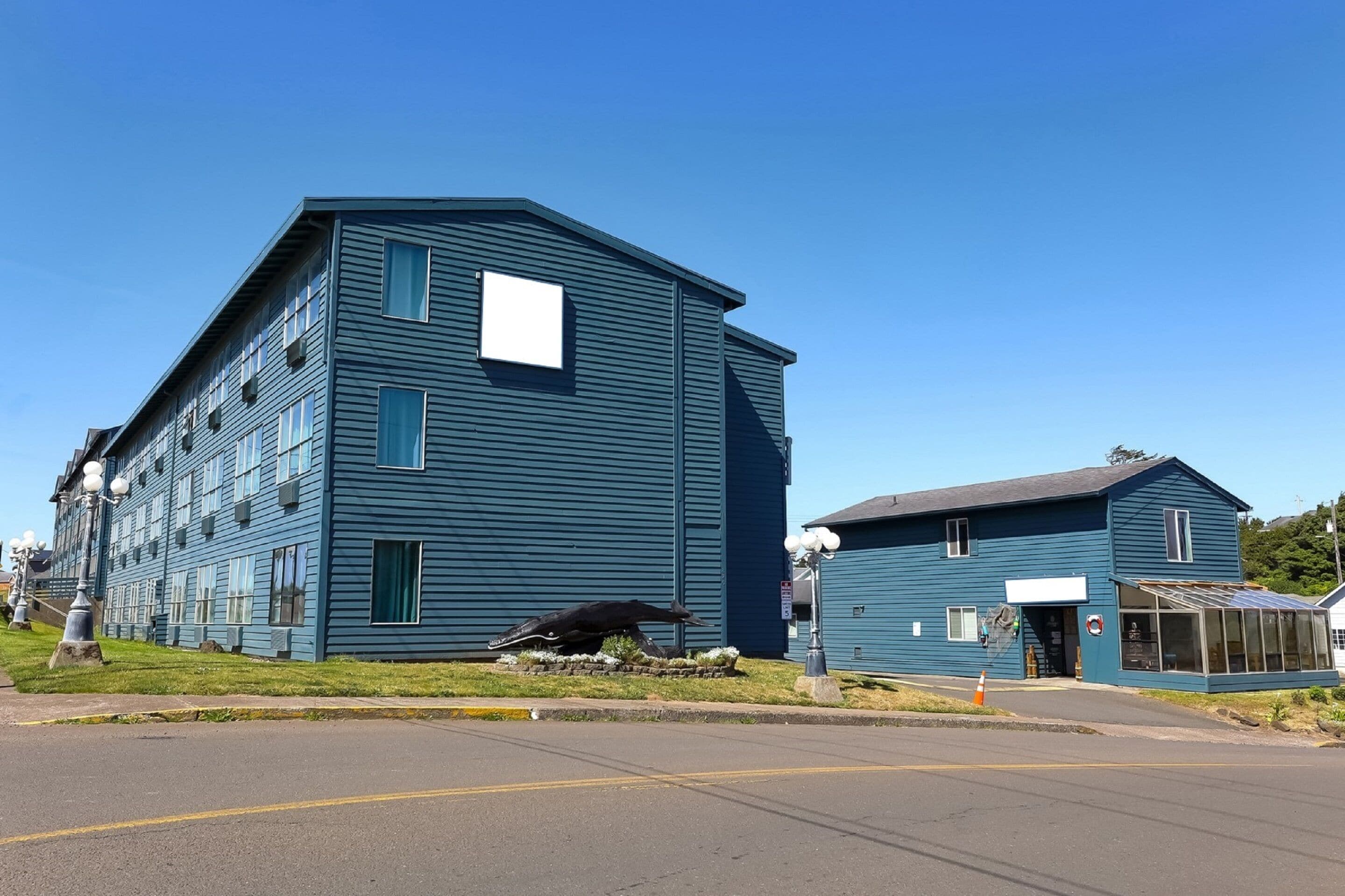 A two-story building with a flat roof and a large window on the second floor.