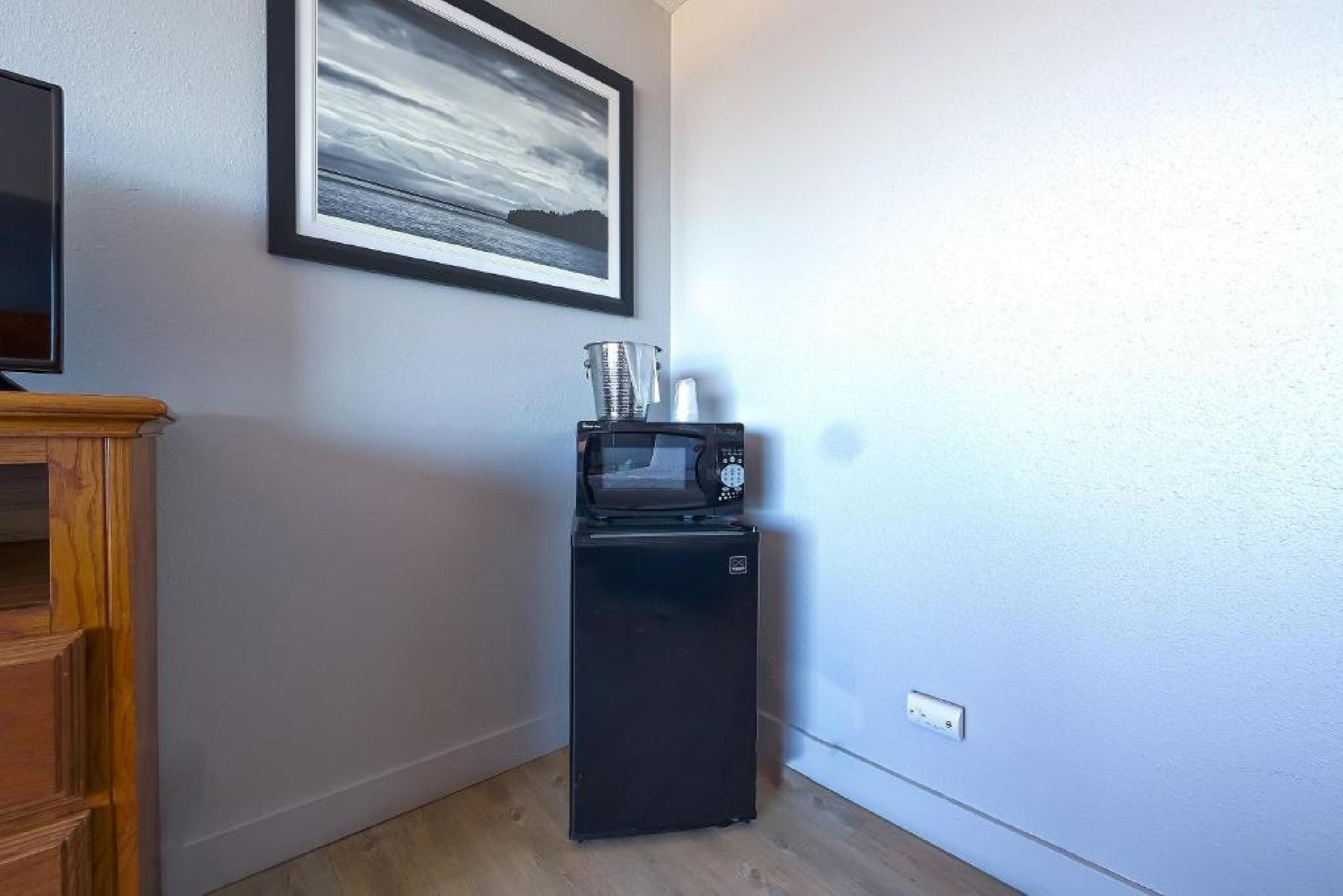Une cuisine compacte équipée d’un four à micro-ondes, d’un petit réfrigérateur et d’un meuble en bois.