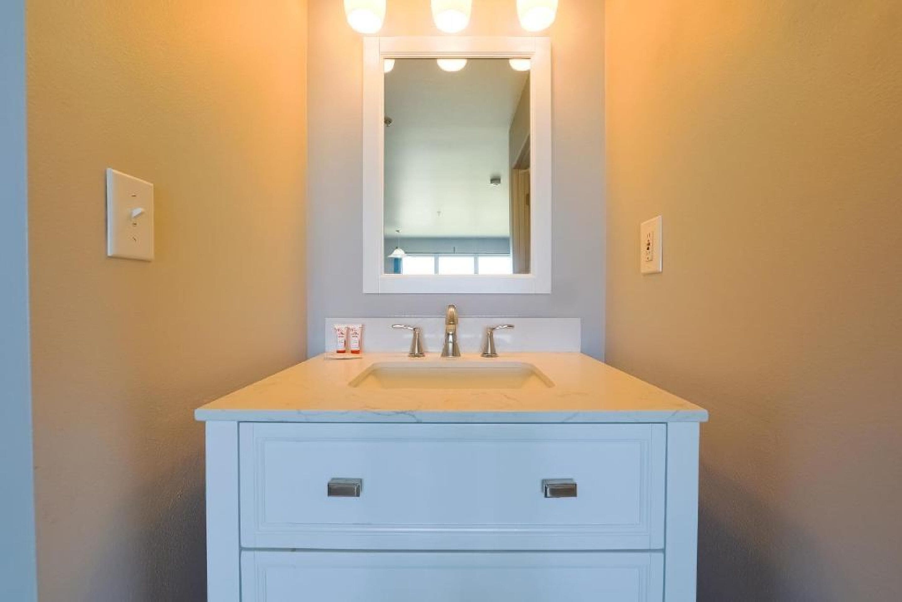 Une salle de bain avec un meuble-lavabo blanc, un miroir et un évier.