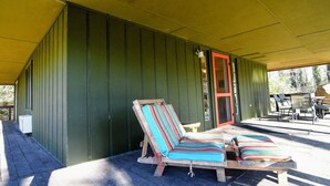 Un espacio de estar techado al aire libre con un banco de madera y una puerta roja.