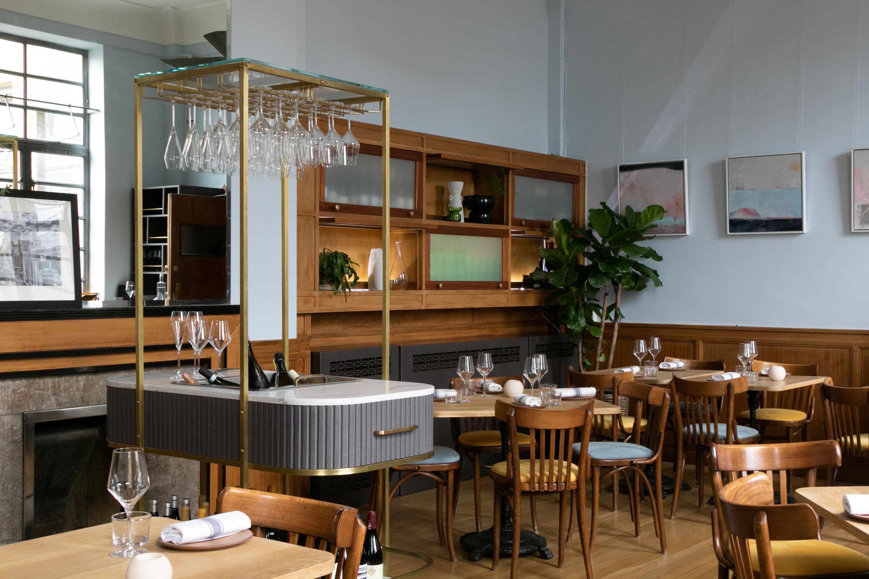 L’intérieur d’un restaurant est aménagé avec des meubles en bois, un bar central et des œuvres d’art accrochées aux murs.