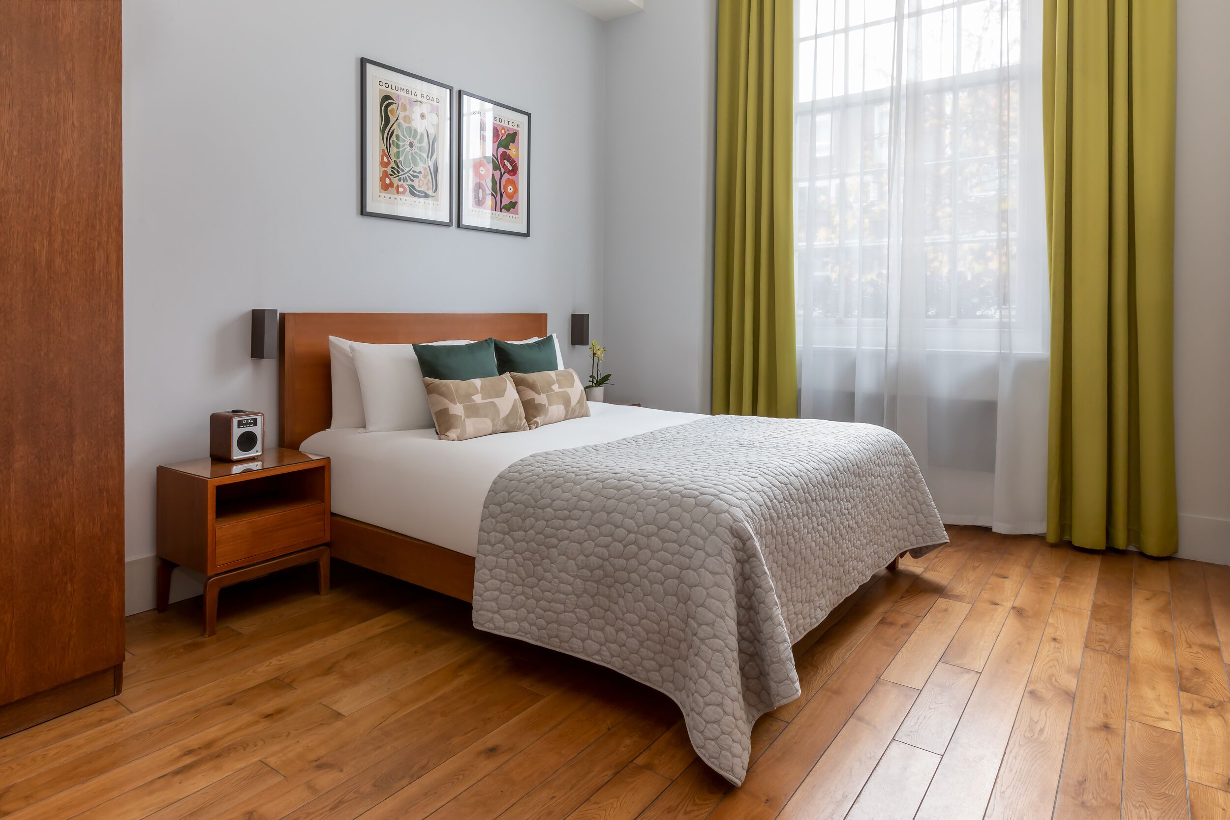 A neatly arranged bedroom with a bed, bedside table, and a window with curtains.