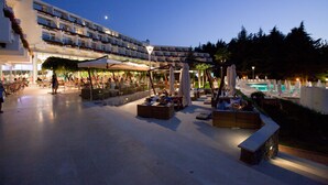 Ein Hotelinnenhof mit Außenmöbeln, einem Pool und Nachthimmel.
