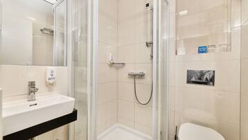 Een moderne badkamer met een douchecabine van glas, een wit wastafelmeubel en een toilet.