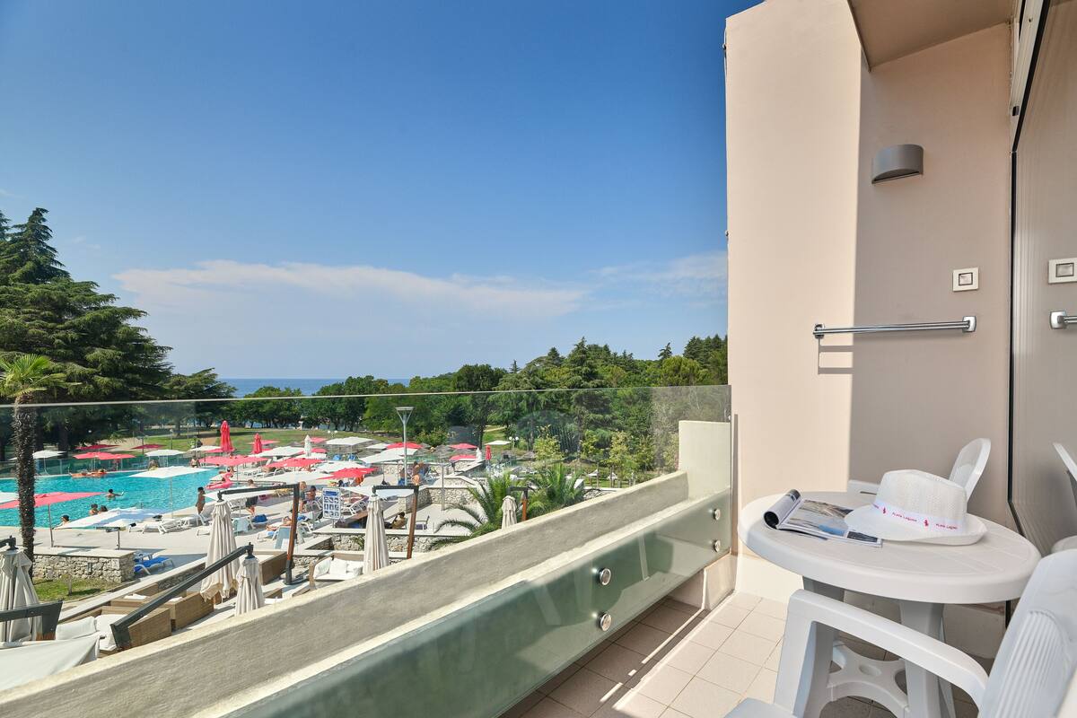 A balcony with a view of a pool area, including lounge chairs and umbrellas.