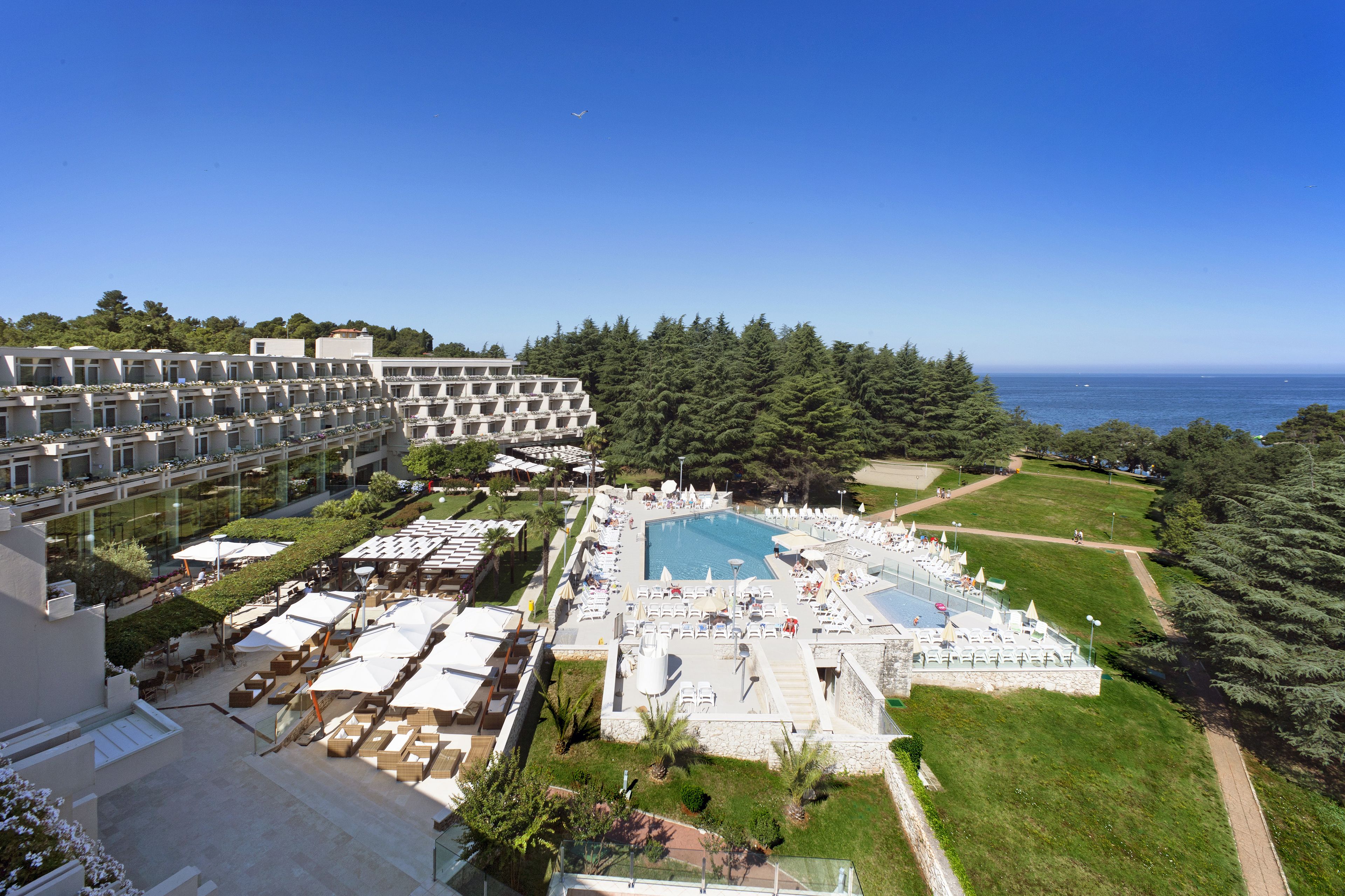 Ein Resort mit großem Pool, Sitzgelegenheiten im Freien und Meerblick.
