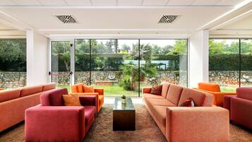Ein modernes Wohnzimmer mit großen Fenstern, roten Sofas und einem zentralen Couchtisch.