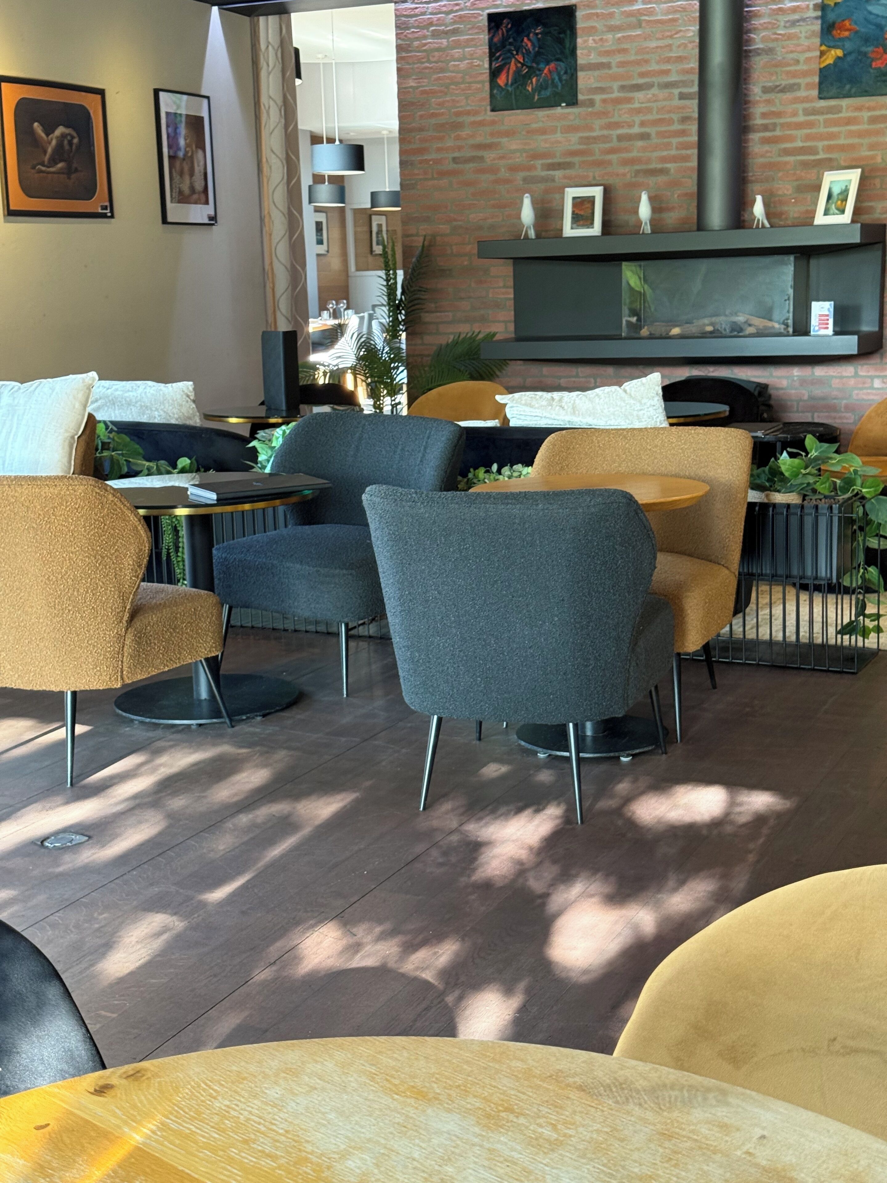 Un café moderno con sillas tapizadas en gris y amarillo, una pared de ladrillo y una chimenea.