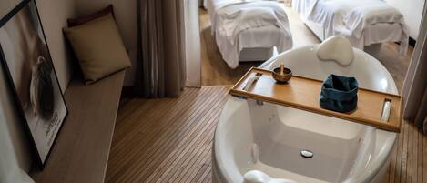 A hotel bathroom with a bathtub, a wooden tray, and a towel rack.