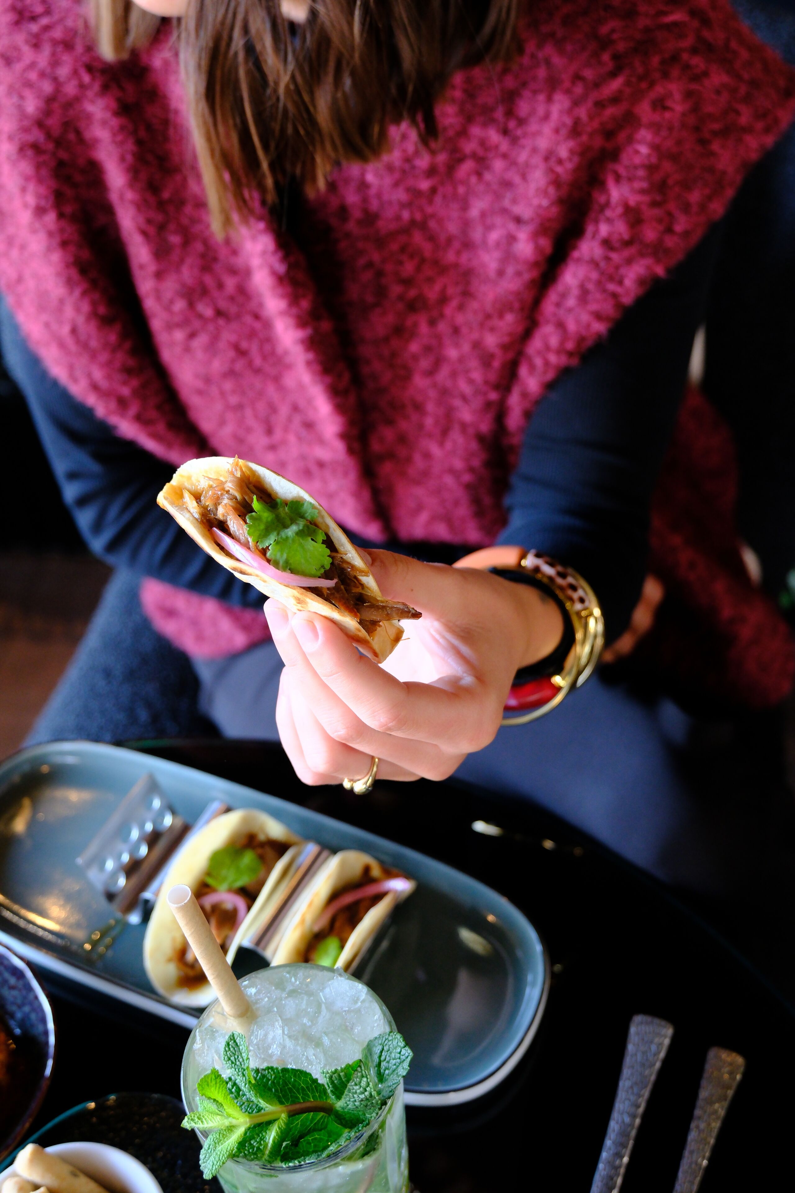 Una persona che tiene un taco con una bevanda davanti.