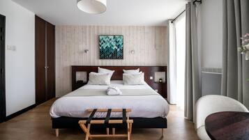 Ein Hotelzimmer mit einem großen Bett, einem Holzkopfstück, Nachttischen, einer Bank und einem Sessel.
