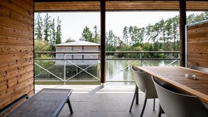 Interior em madeira com vista para um lago e árvores.
