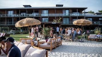 A beachfront hotel with outdoor seating and umbrellas, a bar area, and a sign reading 'La Paillotte'.