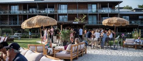 A beachfront hotel with outdoor seating and umbrellas, a bar area, and a sign reading 'La Paillotte'.
