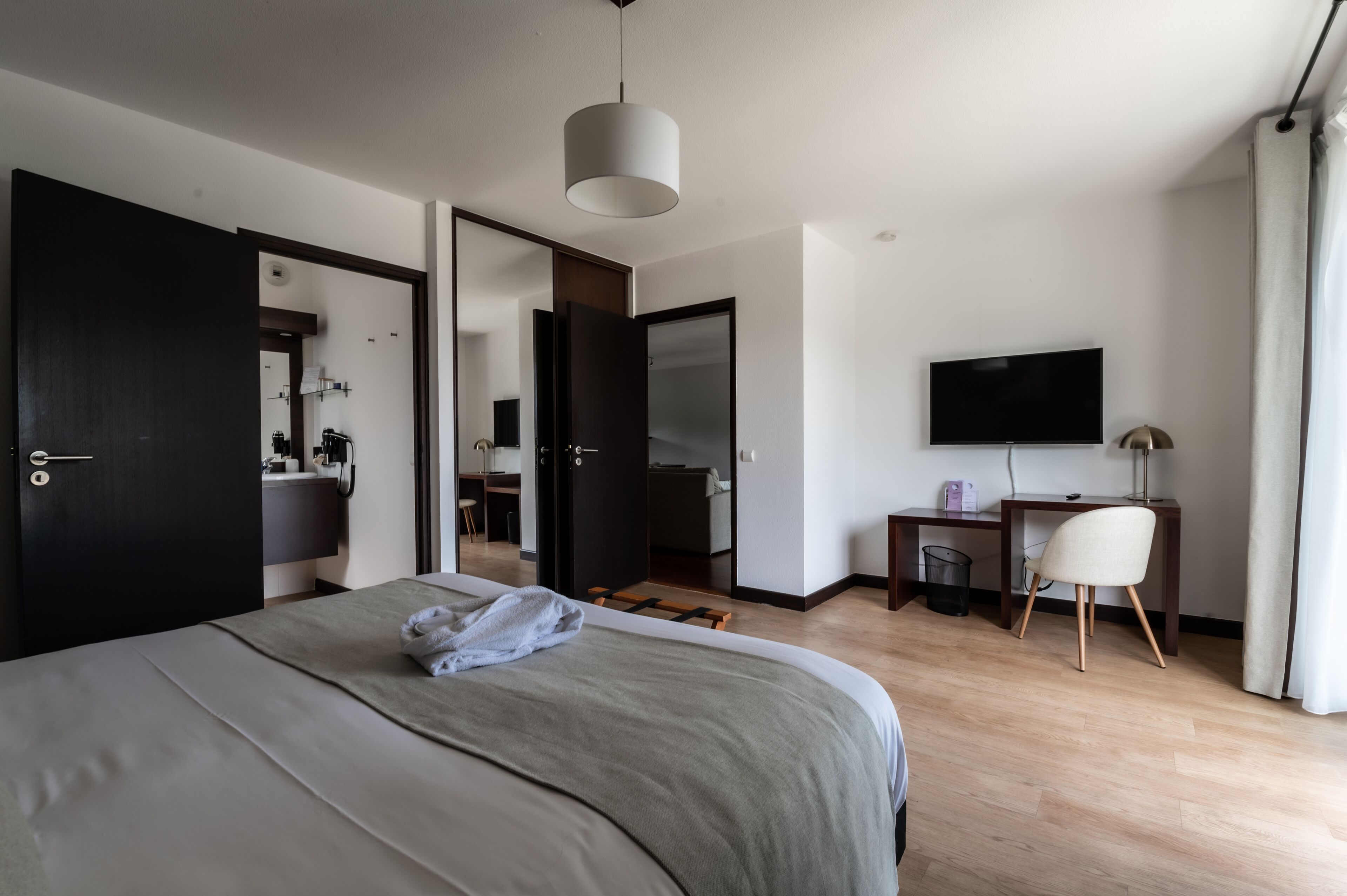 Une chambre d’hôtel moderne équipée d’un grand lit, d’un bureau avec une chaise, d’une télévision et d’un miroir.