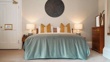 A bedroom with a bed, two bedside tables, a nightstand, a dresser, a mirror, and a wall-mounted decorative piece.
