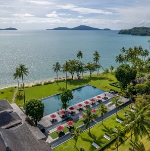 A resort with a pool, palm trees, and a view of the sea. - The Vijitt Resort Phuket (Rawai)