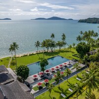 Un resort con piscina, palme e vista sul mare.