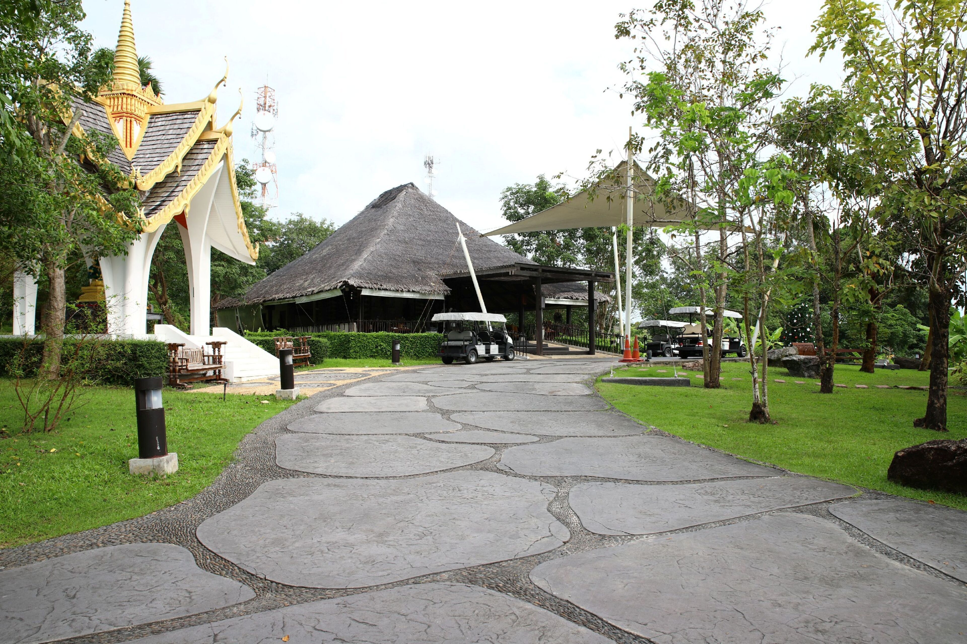 A pathway leading to a traditional building with a thatched roof and golden accents.