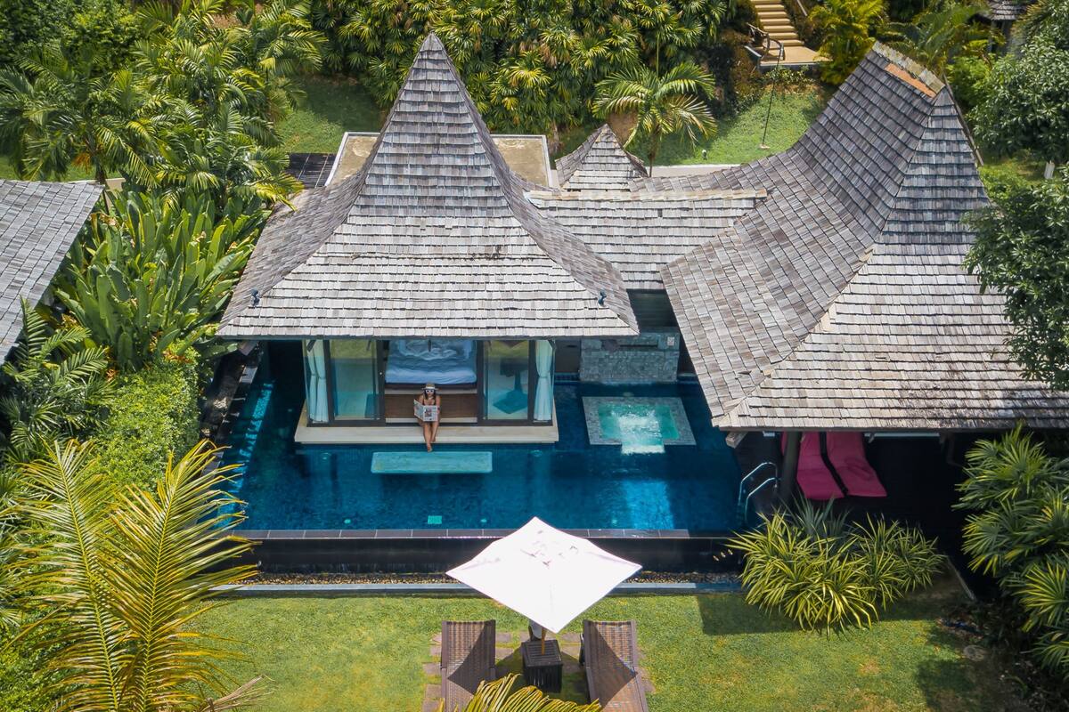 A resort with multiple bungalow-style buildings, a central swimming pool, and lush tropical vegetation.
