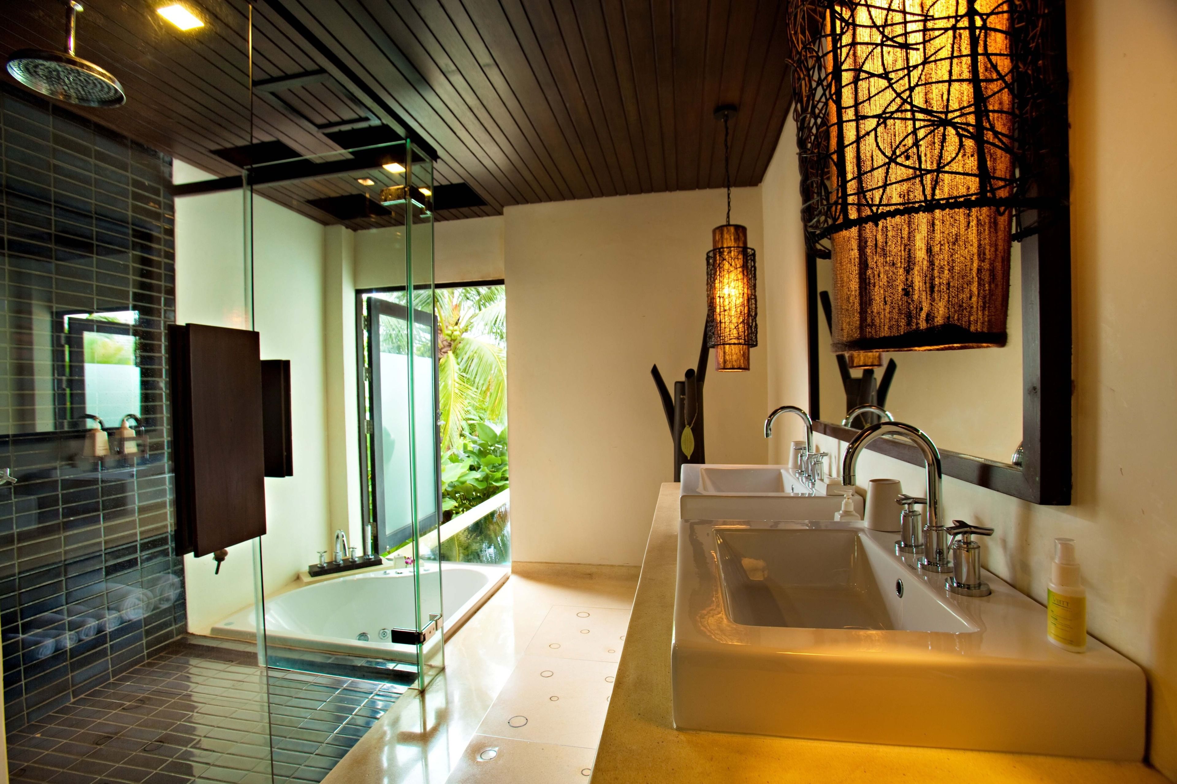 A modern bathroom with a glass shower enclosure, a large bathtub, and a double sink.