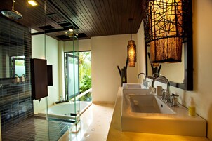 A modern bathroom with a glass shower enclosure, a large bathtub, and a double sink.