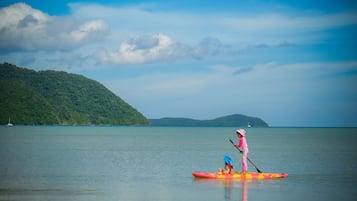 A calm lake with a person paddleboarding in a pink outfit and another in a kayak.