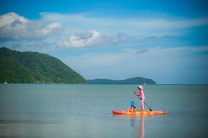 Un lago tranquilo con una persona haciendo paddleboard con un atuendo rosa y otra en kayak.