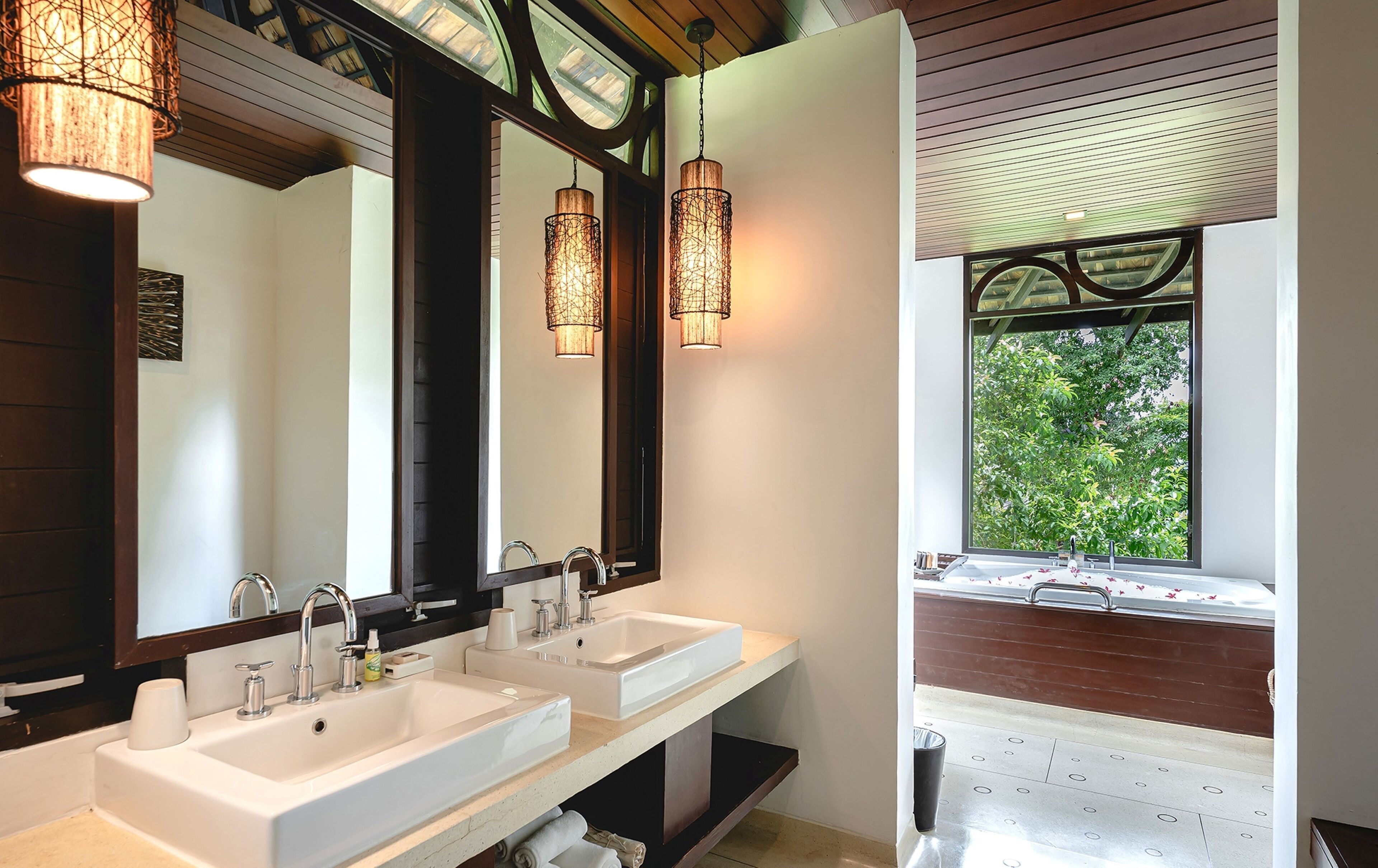 A modern bathroom with two sinks, a large mirror, and pendant lighting.