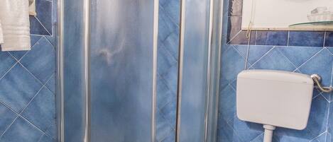 A bathroom with a glass-enclosed shower, a toilet, and a bidet.