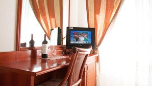 A wooden desk with a television displaying a cooking show, a wine bottle, and glasses. - Mediterraneo (Cefalù)