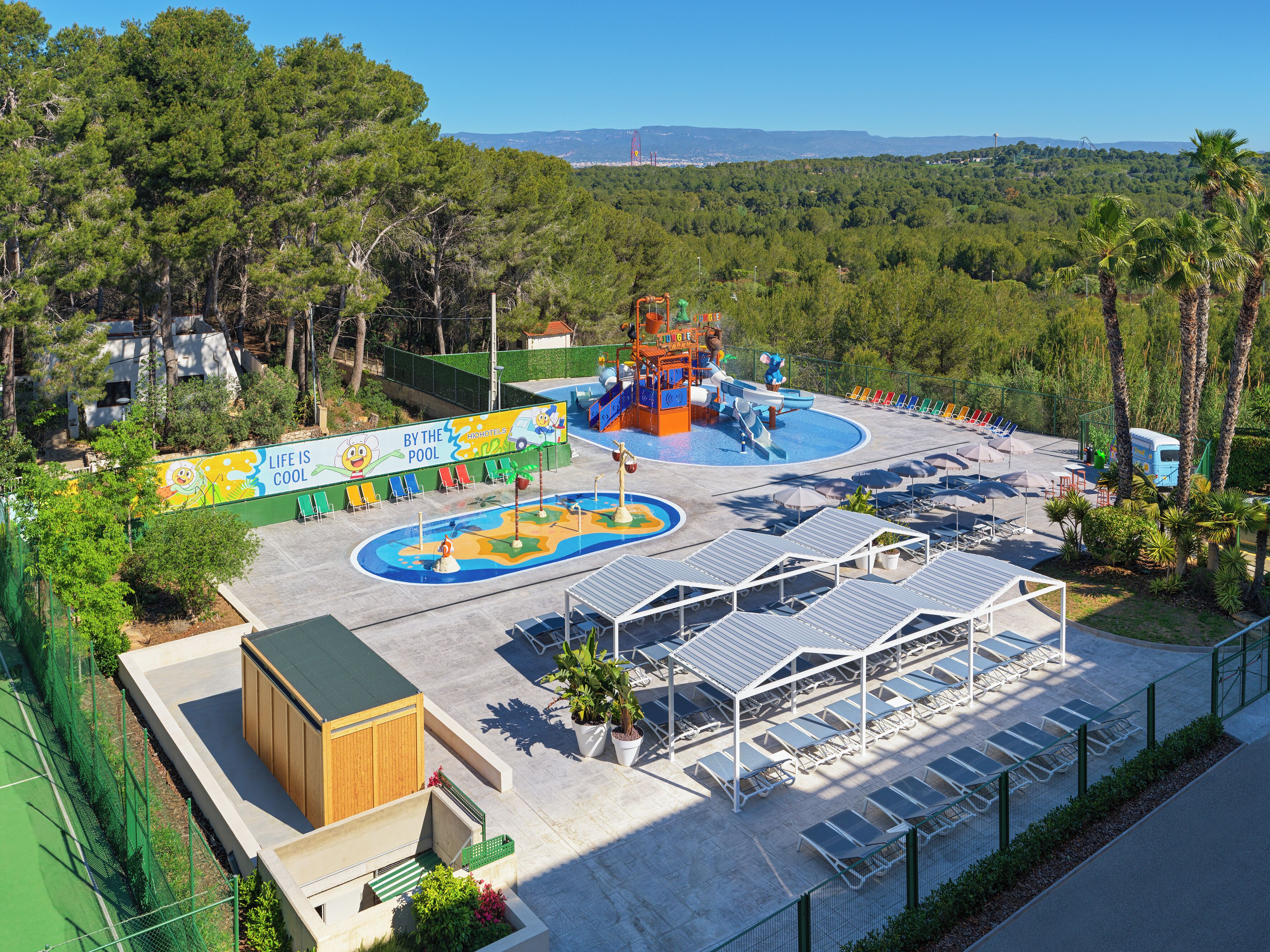 Een waterpark met een zwembad, glijbanen en ligbedden.